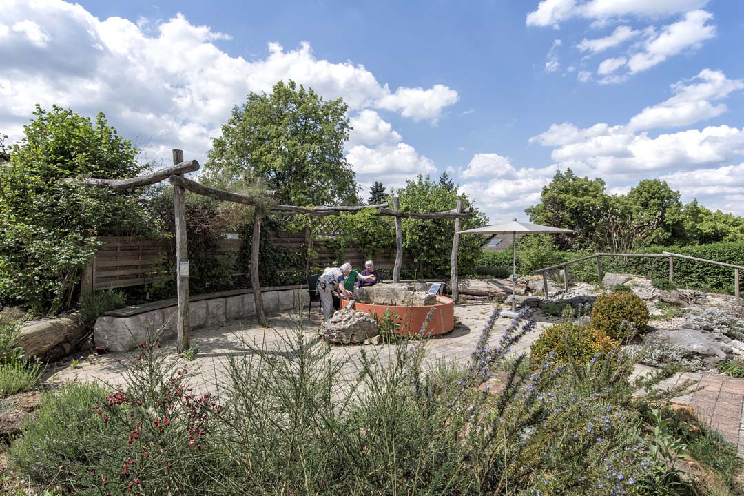 Dieses Bild zeigt das AWO Seniorenzentrum Weißenburg von außen: ein Garten mit einem schönen Wasserbassin